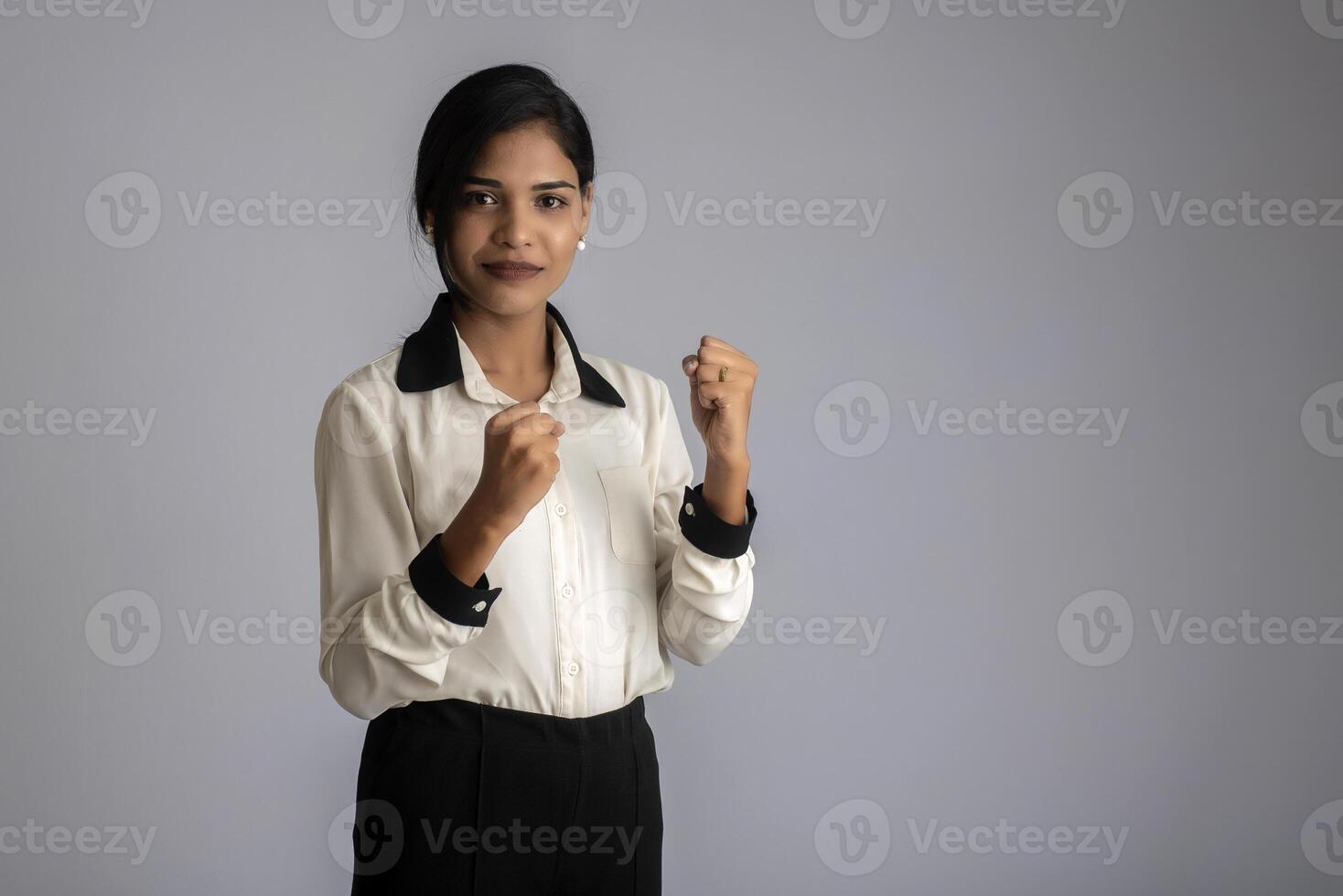 Young smiling girl showing happiness of success on a grey background photo