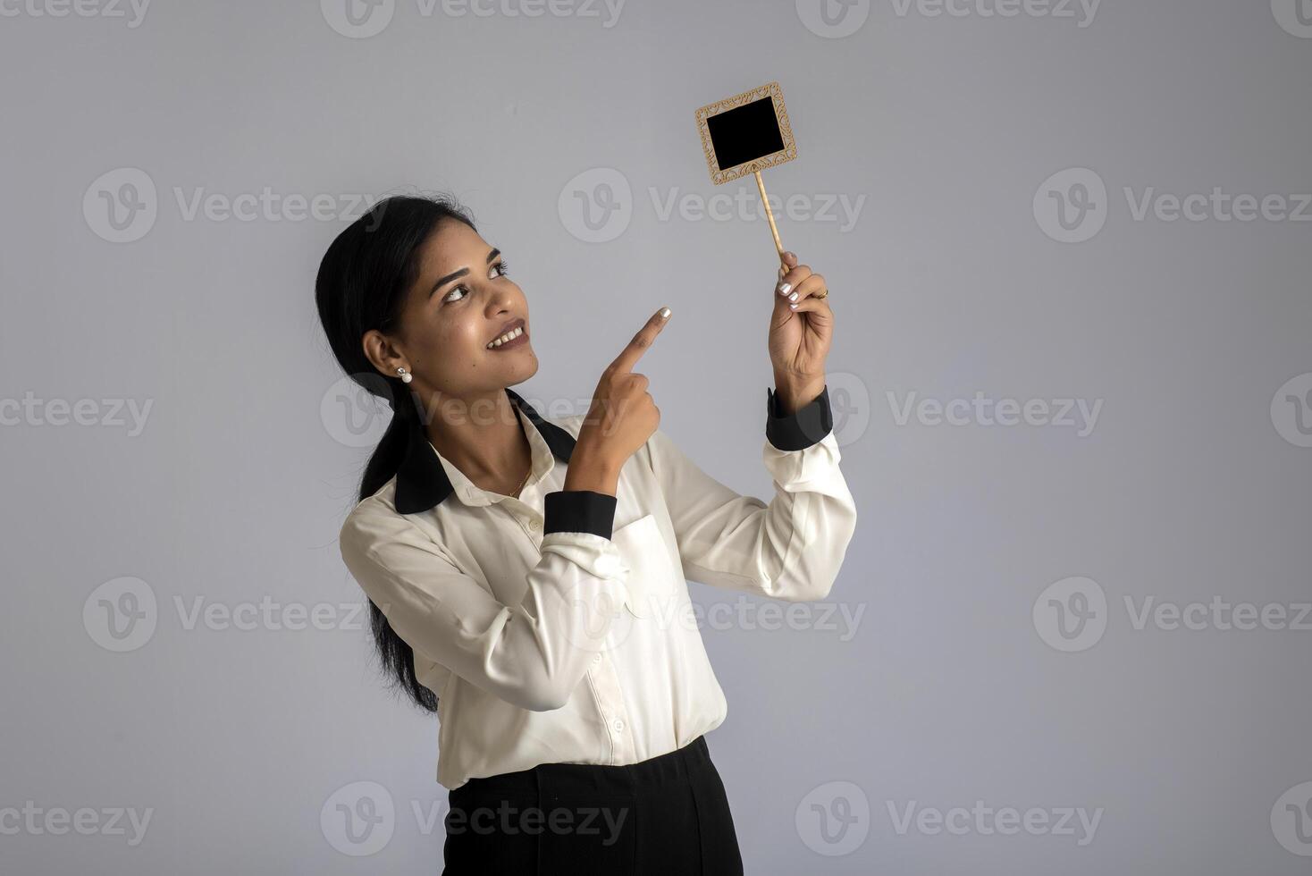 young woman or business woman holding a little cutout board in her hands on a gray background. photo