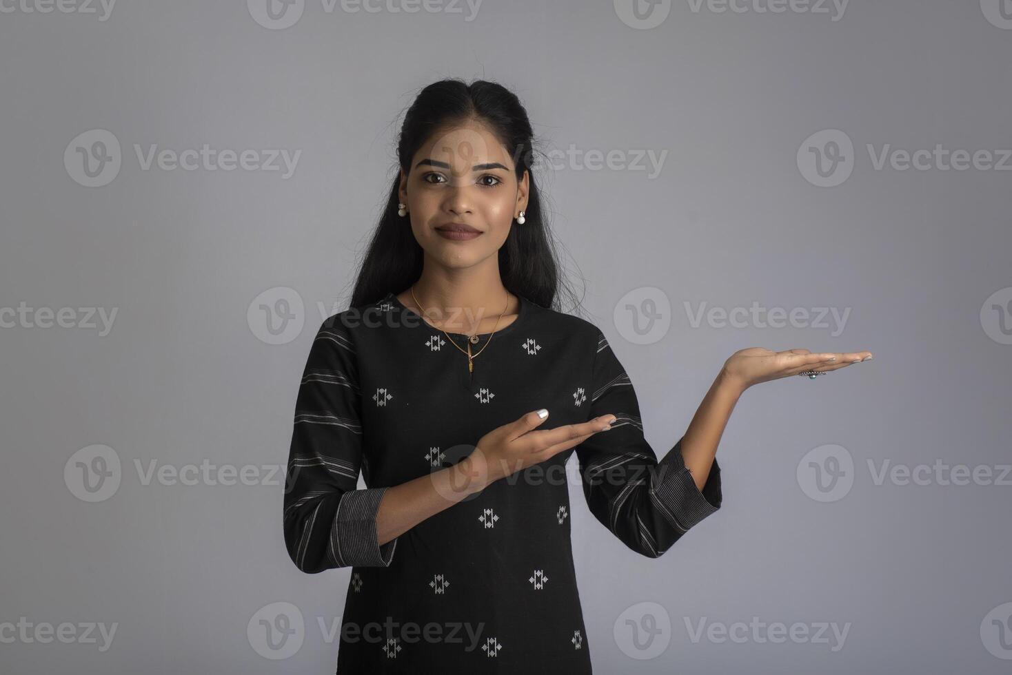 Beautiful girl holding and presenting something in the hand with a happy smiling face. photo