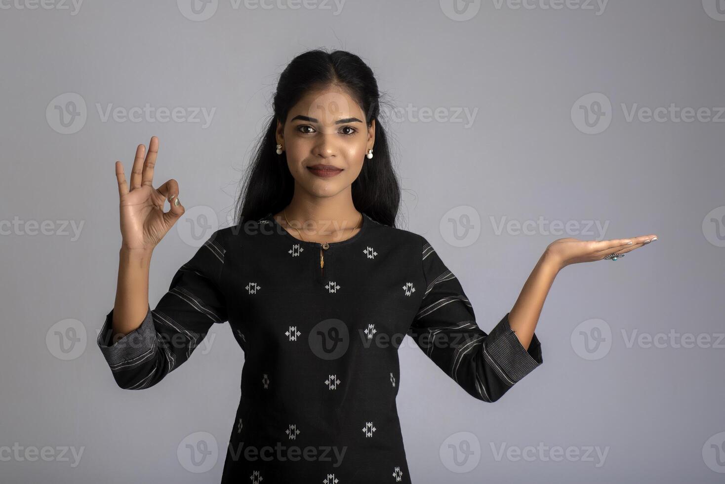 Beautiful girl holding and presenting something in the hand with a happy smiling face. photo
