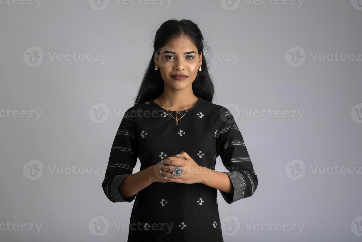 Portrait of a young beautiful cute cheerful girl smiling looking at the camera on gray background photo