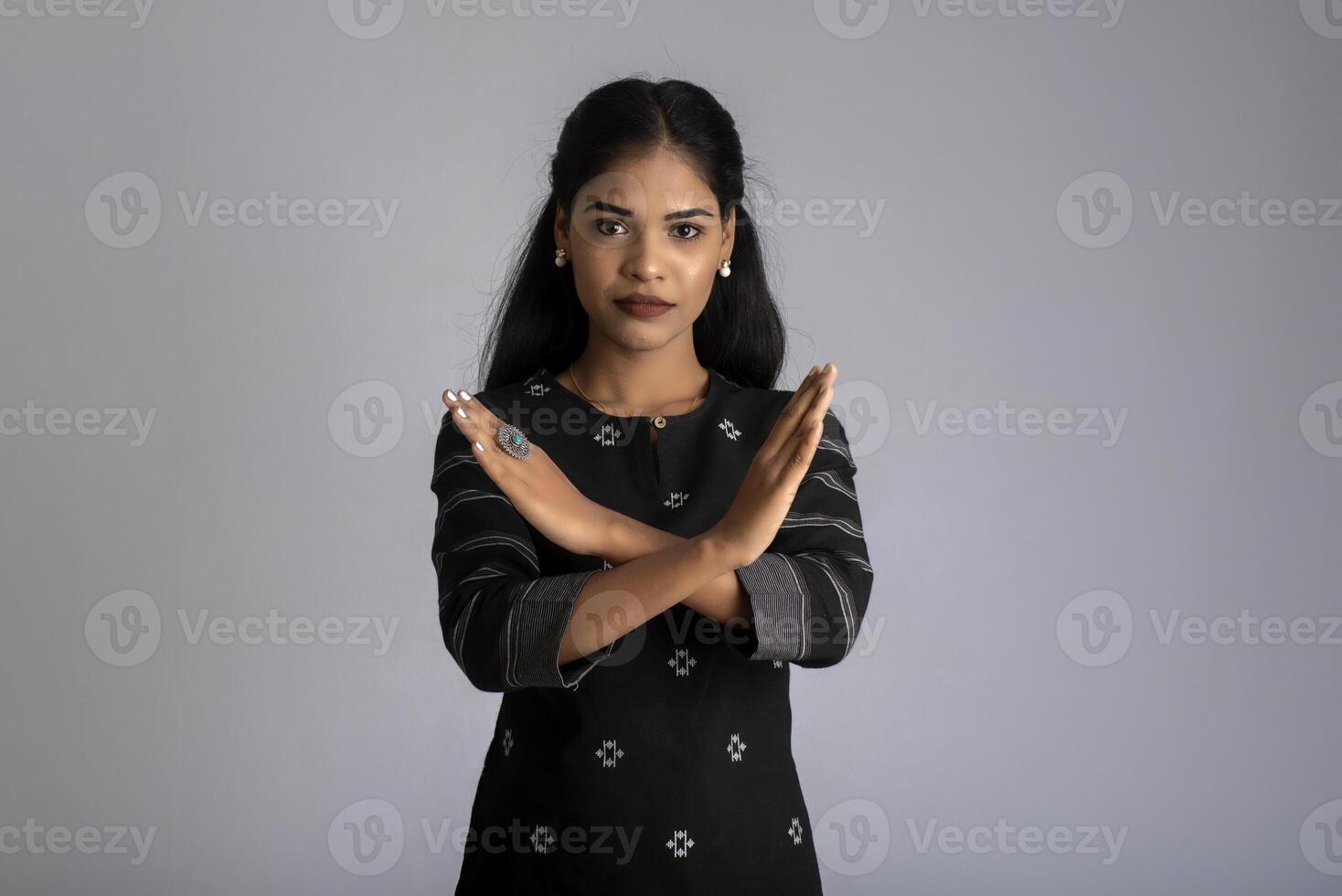 Portrait of a beautiful girl showing stop sign on a grey background photo