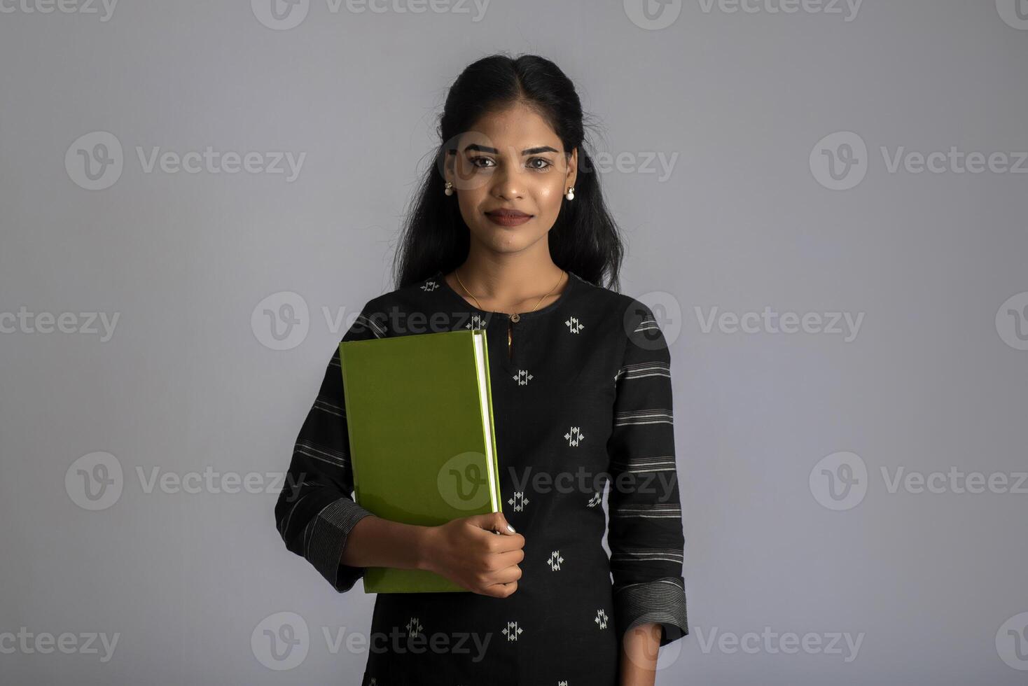 Pretty young girl holding book and posing on grey background photo