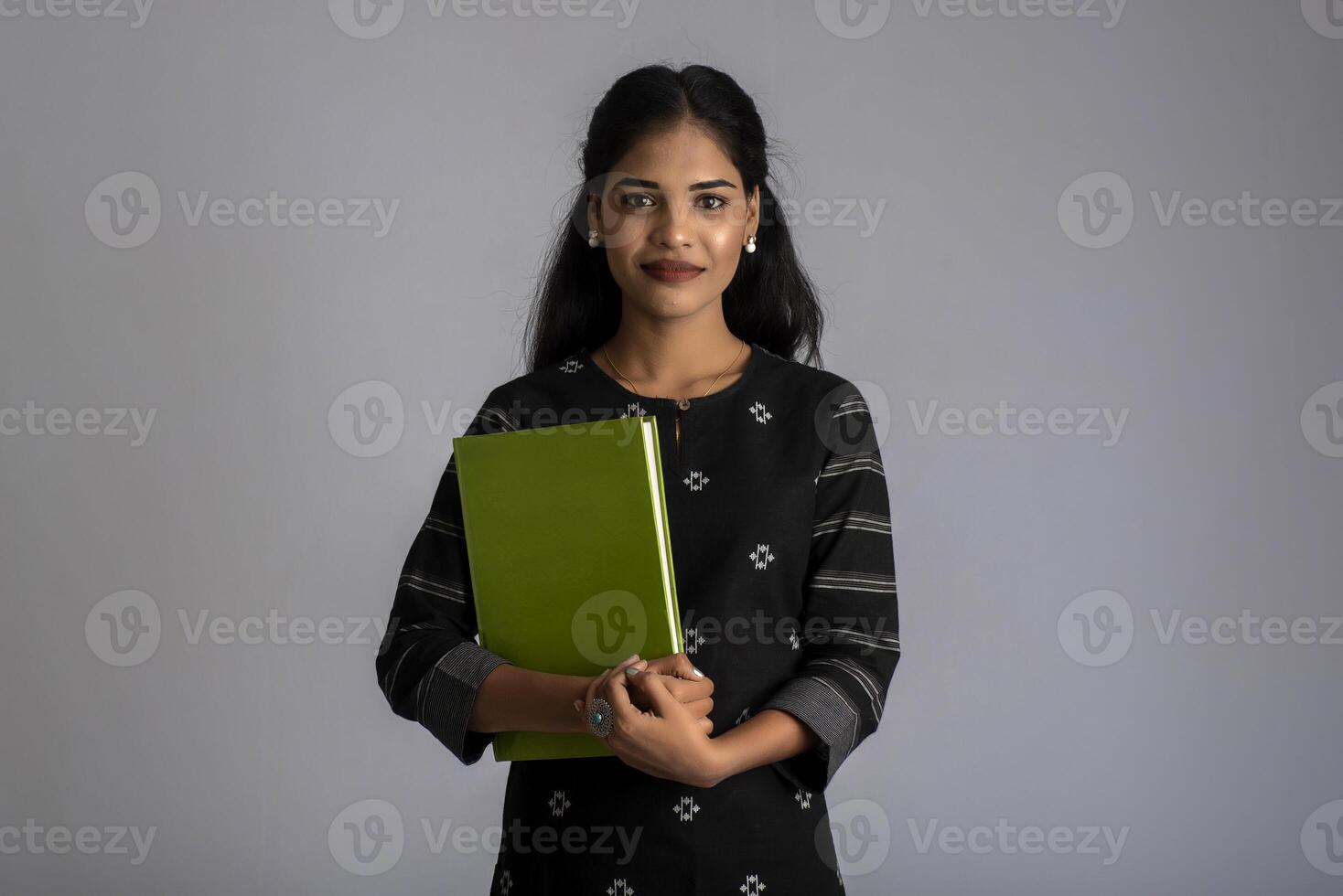 Pretty young girl holding book and posing on grey background photo