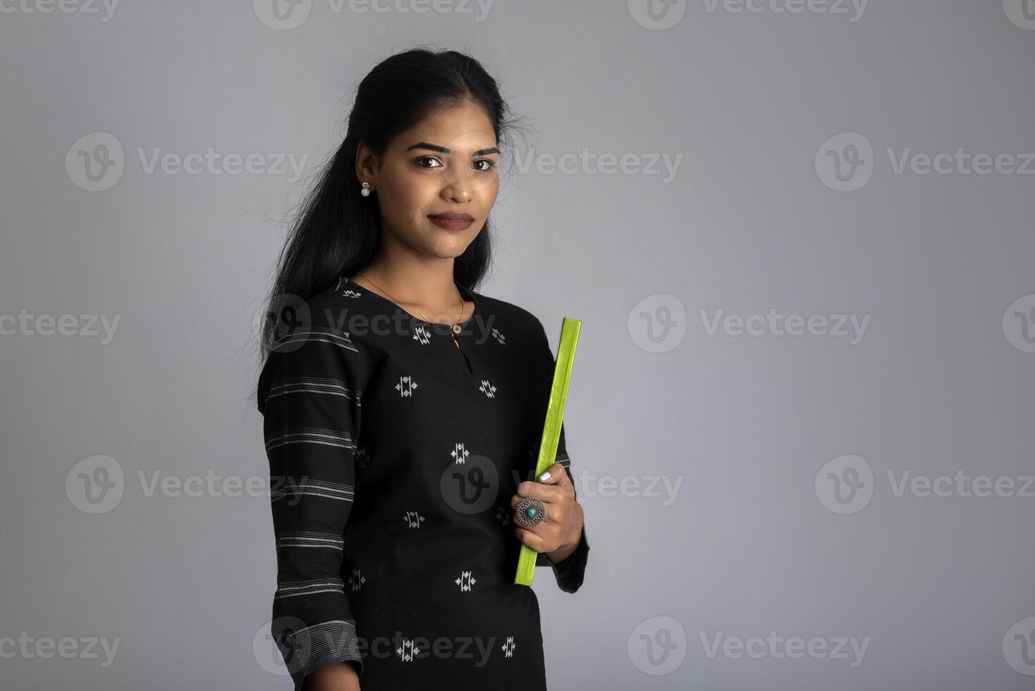 Pretty young girl holding book and posing on grey background photo