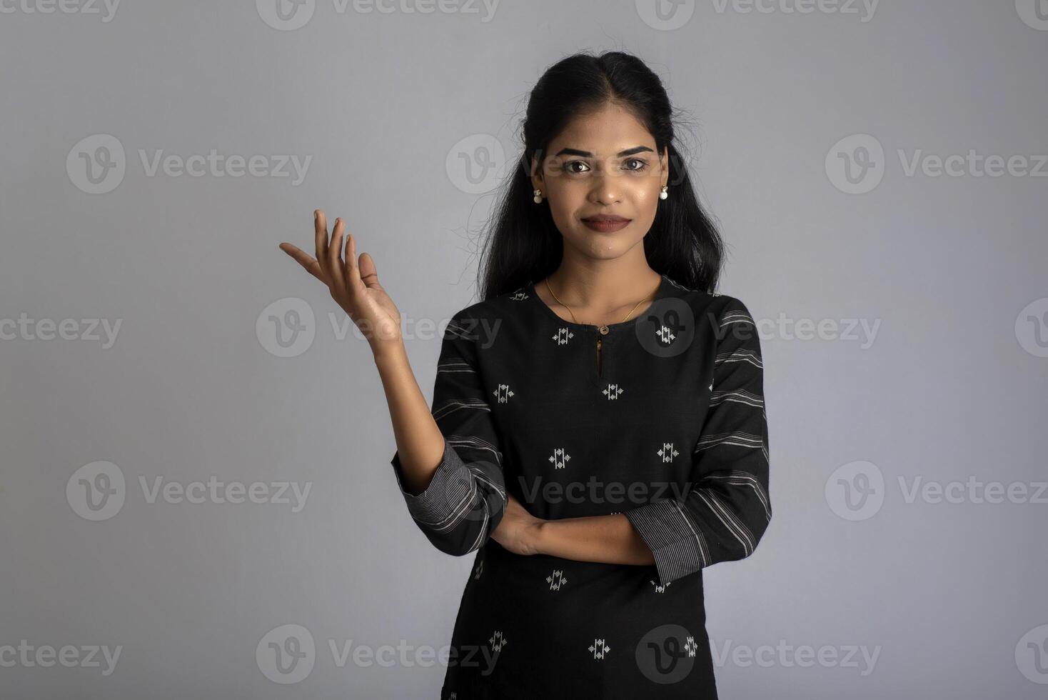 Beautiful girl holding and presenting something in the hand with a happy smiling face. photo