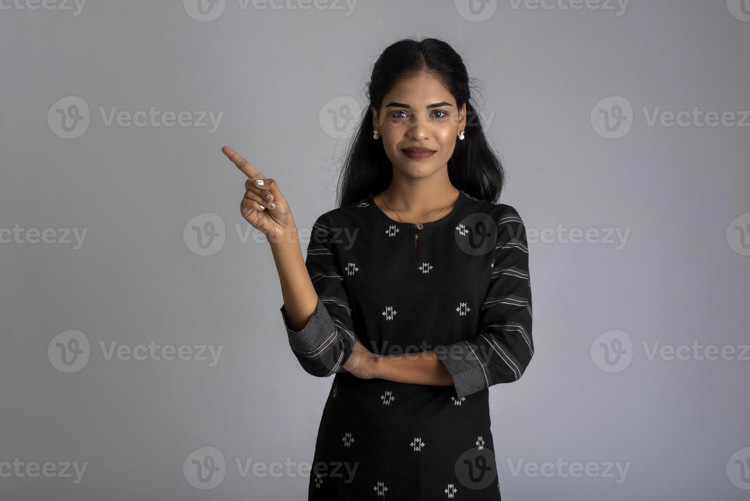 Beautiful girl holding and presenting something in the hand with a happy smiling face. photo