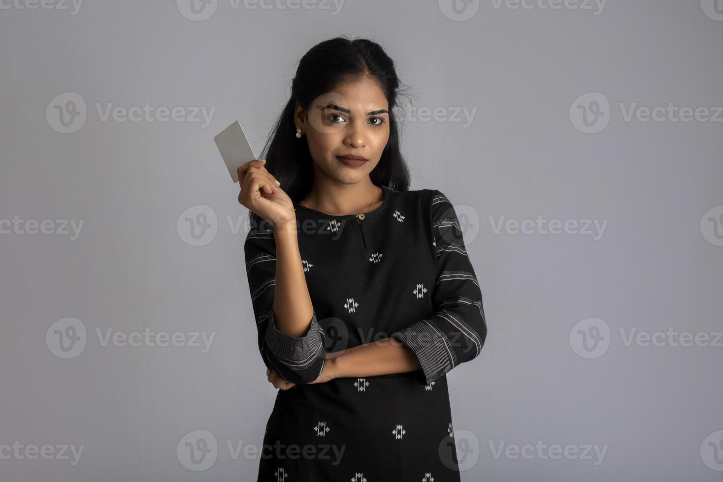 Young smiling beautiful woman or girl presenting credit card in hand showing trust and confidence for making payment. photo
