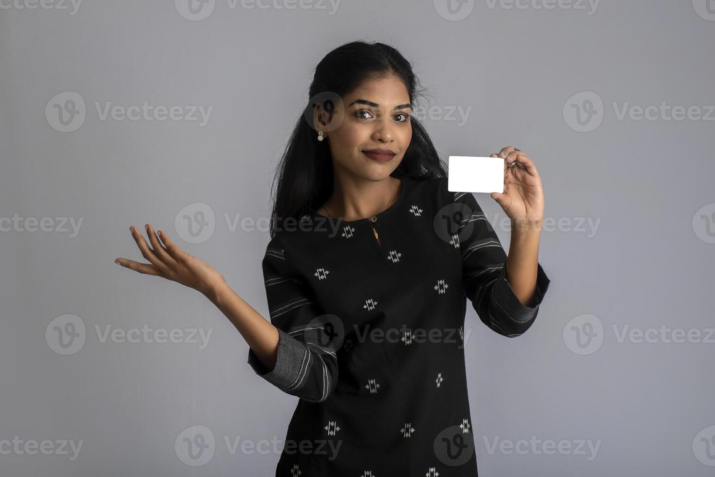Young smiling beautiful woman or girl presenting credit card in hand showing trust and confidence for making payment. photo
