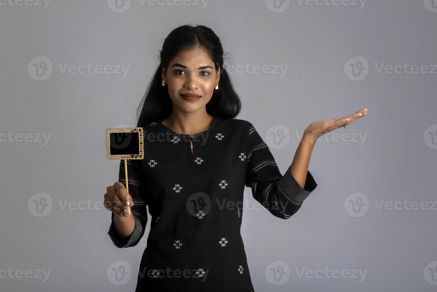 A young woman or businesswoman holding a little cutout board in her hands on a gray background. photo