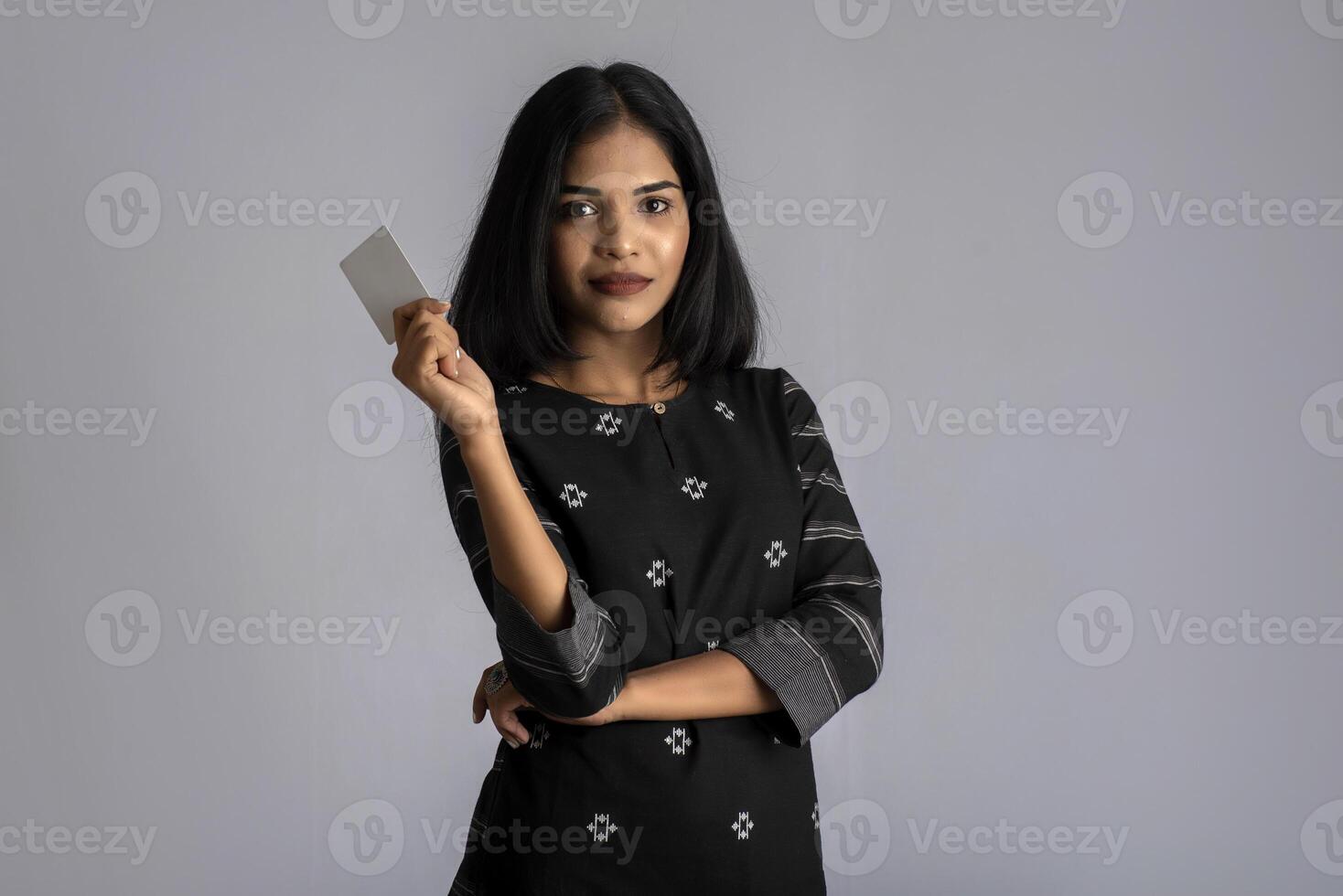 Young smiling beautiful woman or girl presenting credit card in hand showing trust and confidence for making payment. photo