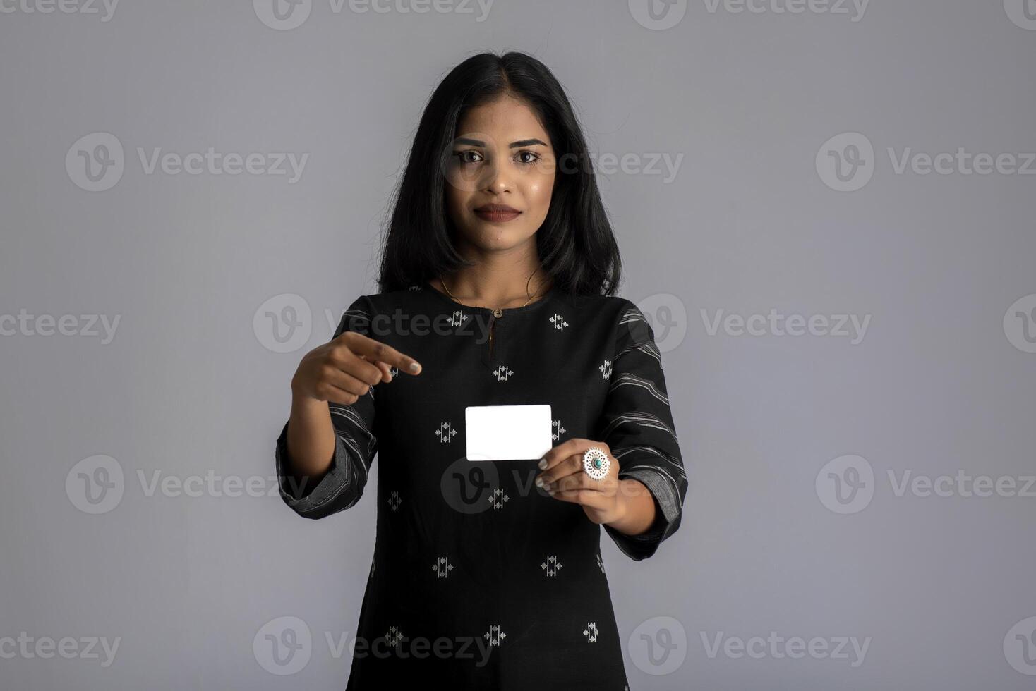 Young smiling beautiful woman or girl presenting credit card in hand showing trust and confidence for making payment. photo