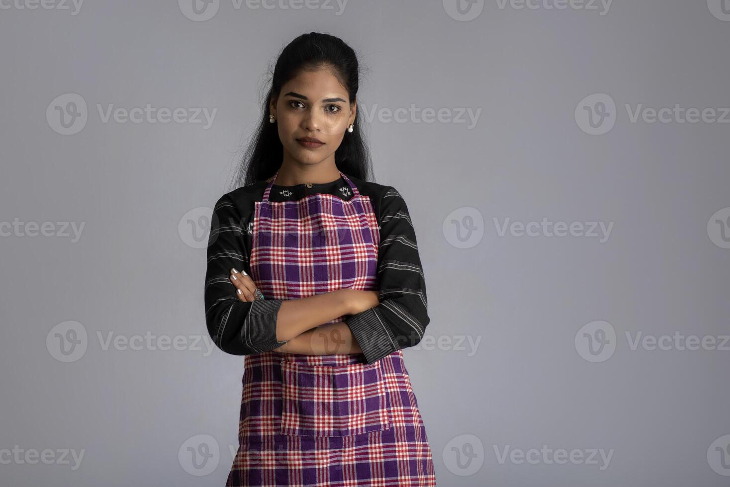 Portrait of Indian woman chef or cook in an apron on grey background. photo