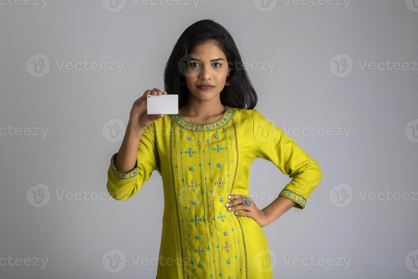 Young smiling beautiful girl posing with a credit card on grey background. photo