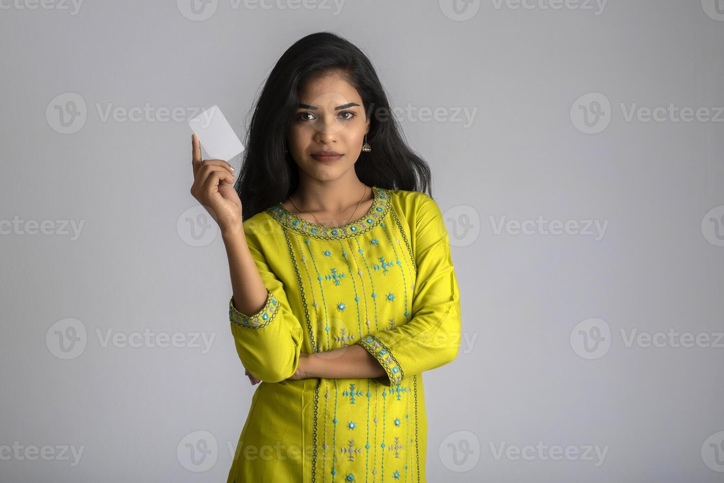 Young smiling beautiful girl posing with a credit card on grey background. photo