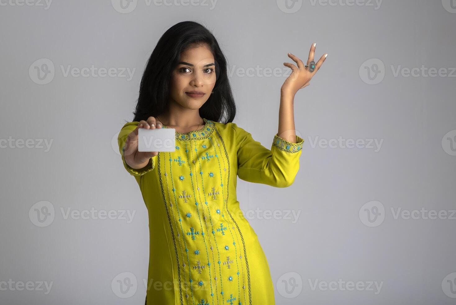 Young smiling beautiful girl posing with a credit card on grey background. photo