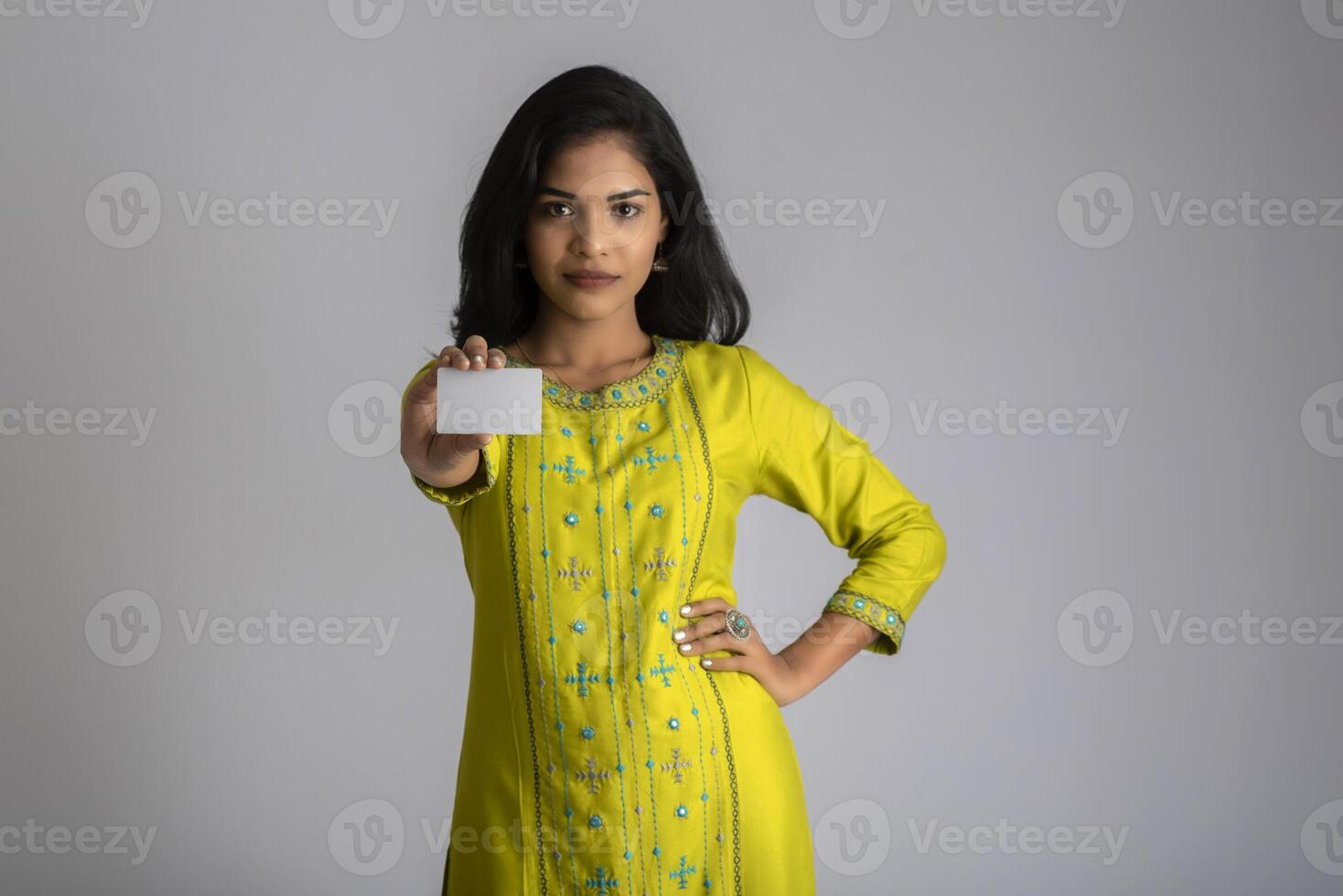 Young smiling beautiful girl posing with a credit card on grey background. photo