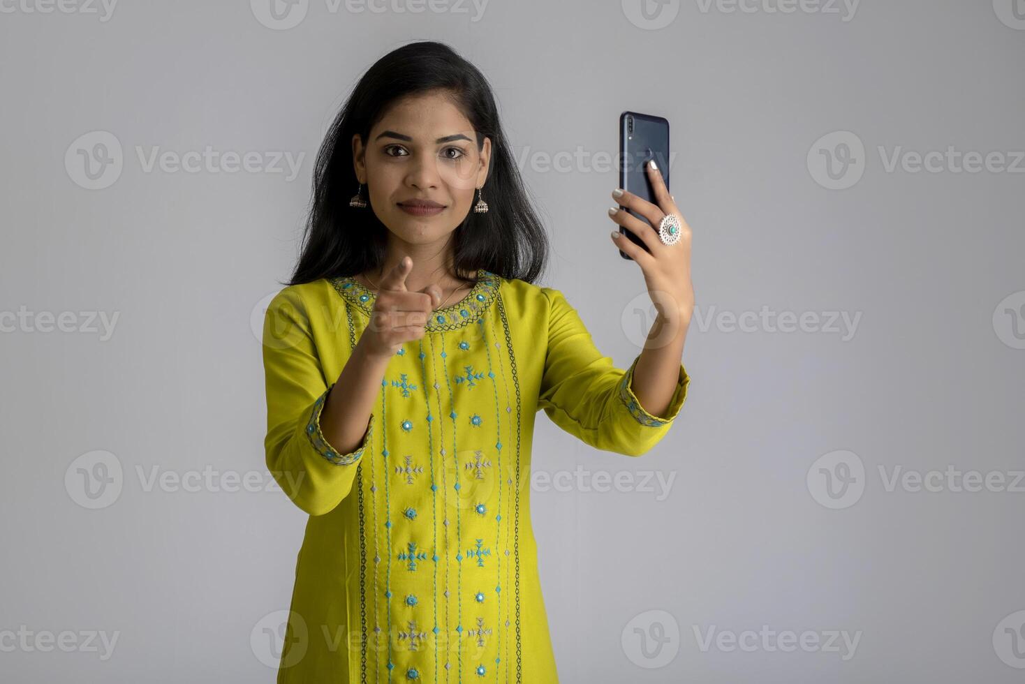 Young girl using mobile phone or smartphone on gray background photo