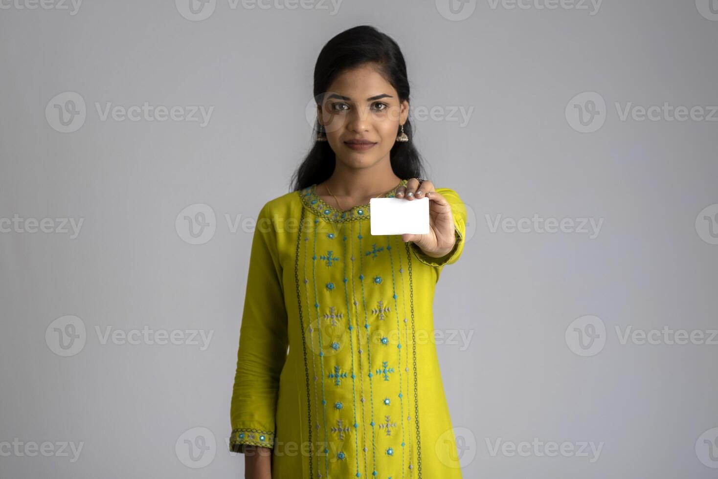 Young smiling beautiful girl posing with a credit card on grey background. photo