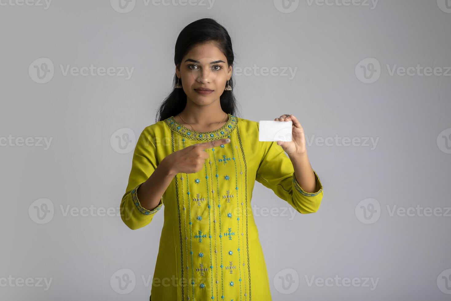 Young smiling beautiful girl posing with a credit card on grey background. photo