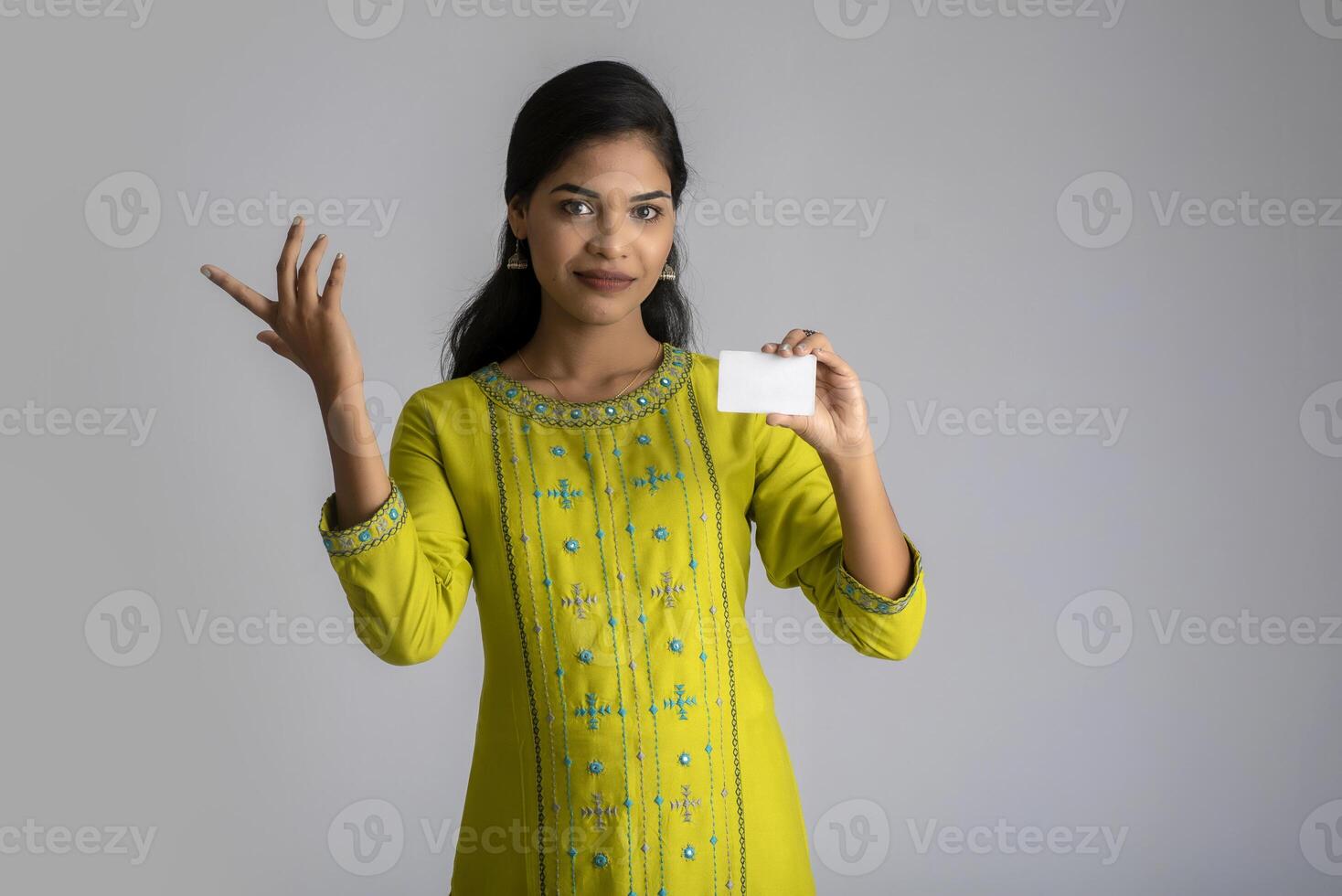 Young smiling beautiful girl posing with a credit card on grey background. photo