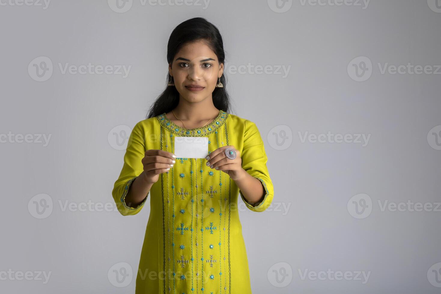 Young smiling beautiful girl posing with a credit card on grey background. photo