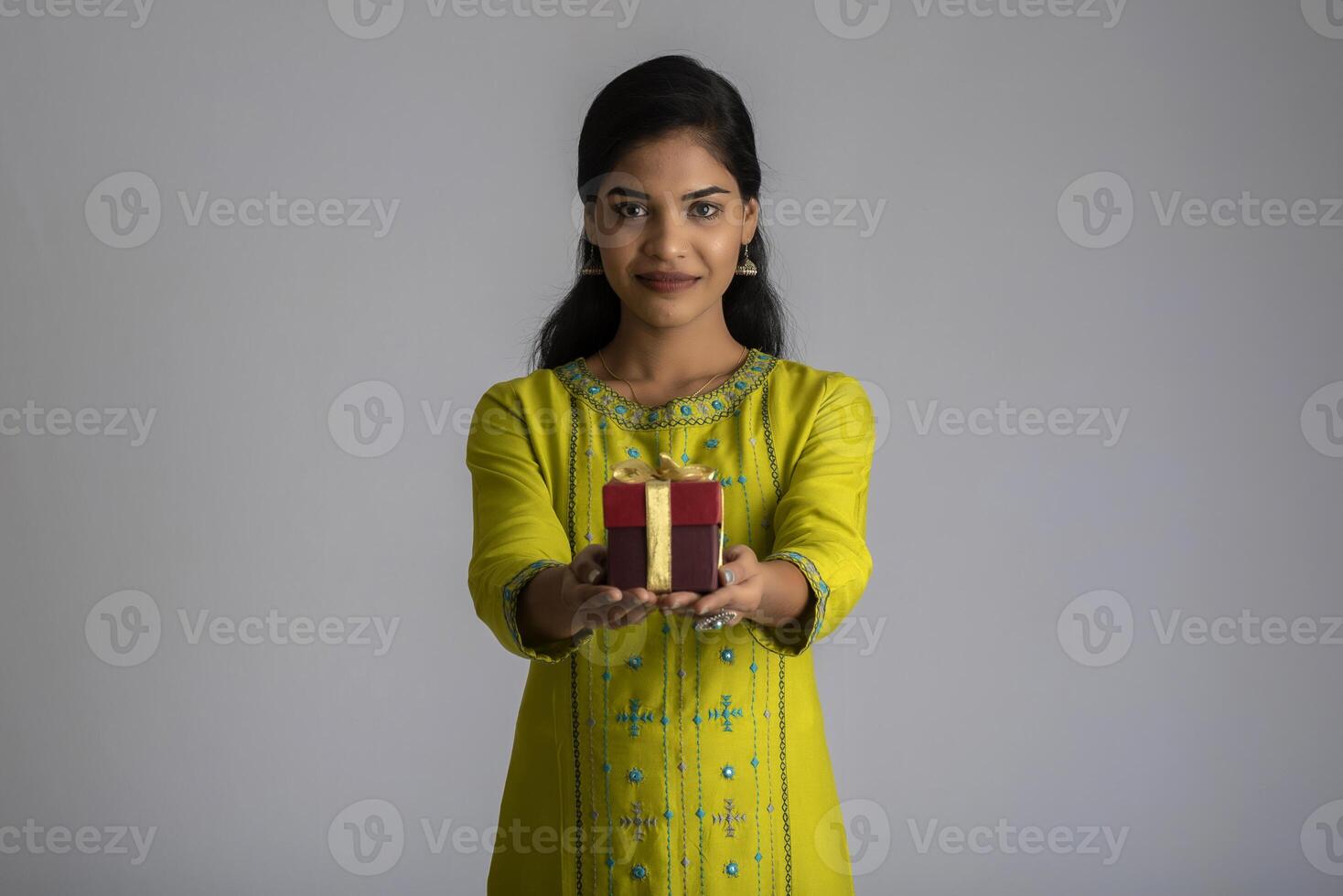 Portrait of young happy smiling woman Girl holding gift box on a grey background. photo
