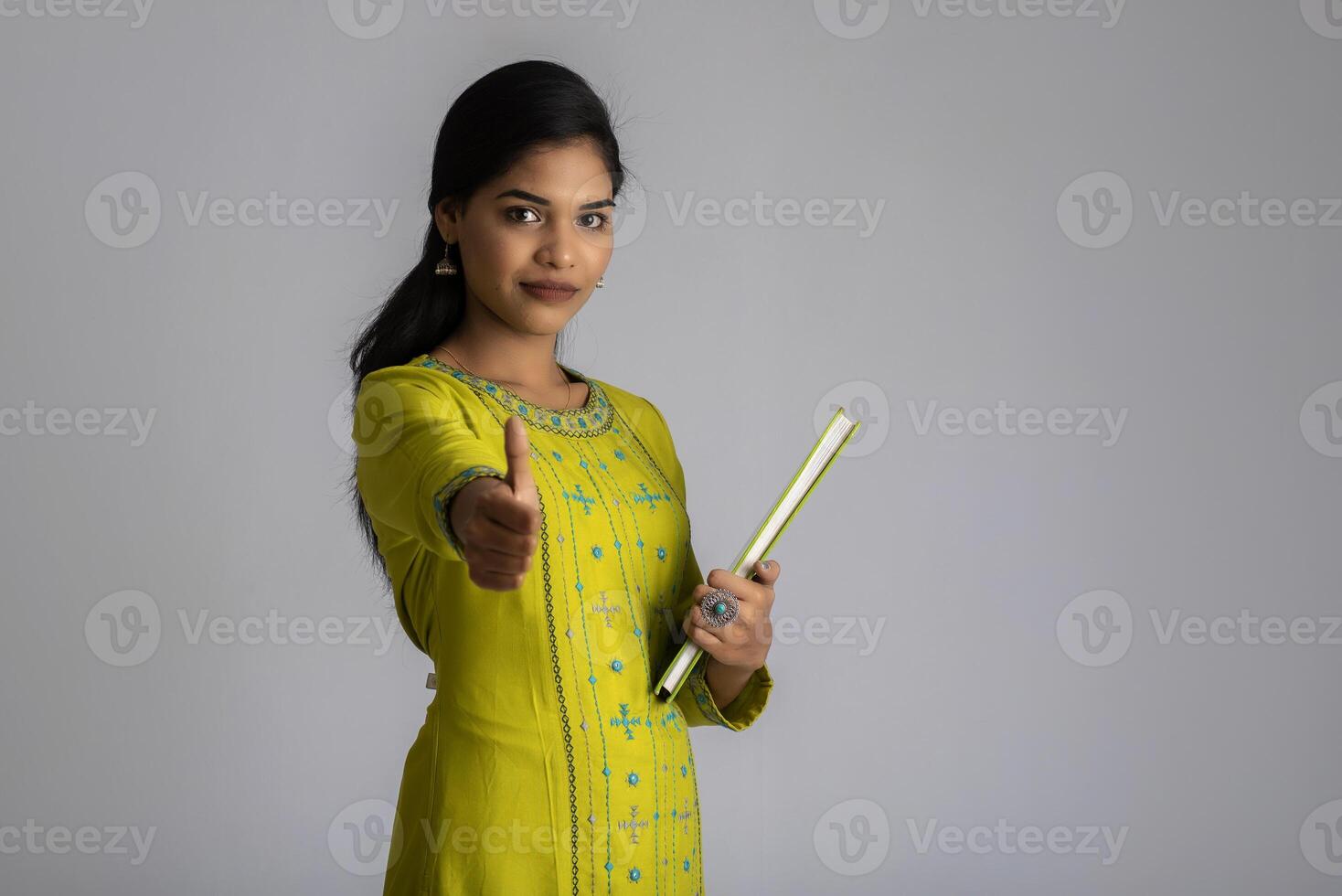 Pretty young girl posing with the book on grey background photo