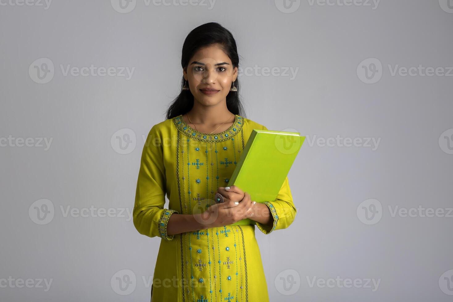 Pretty young girl posing with the book on grey background photo