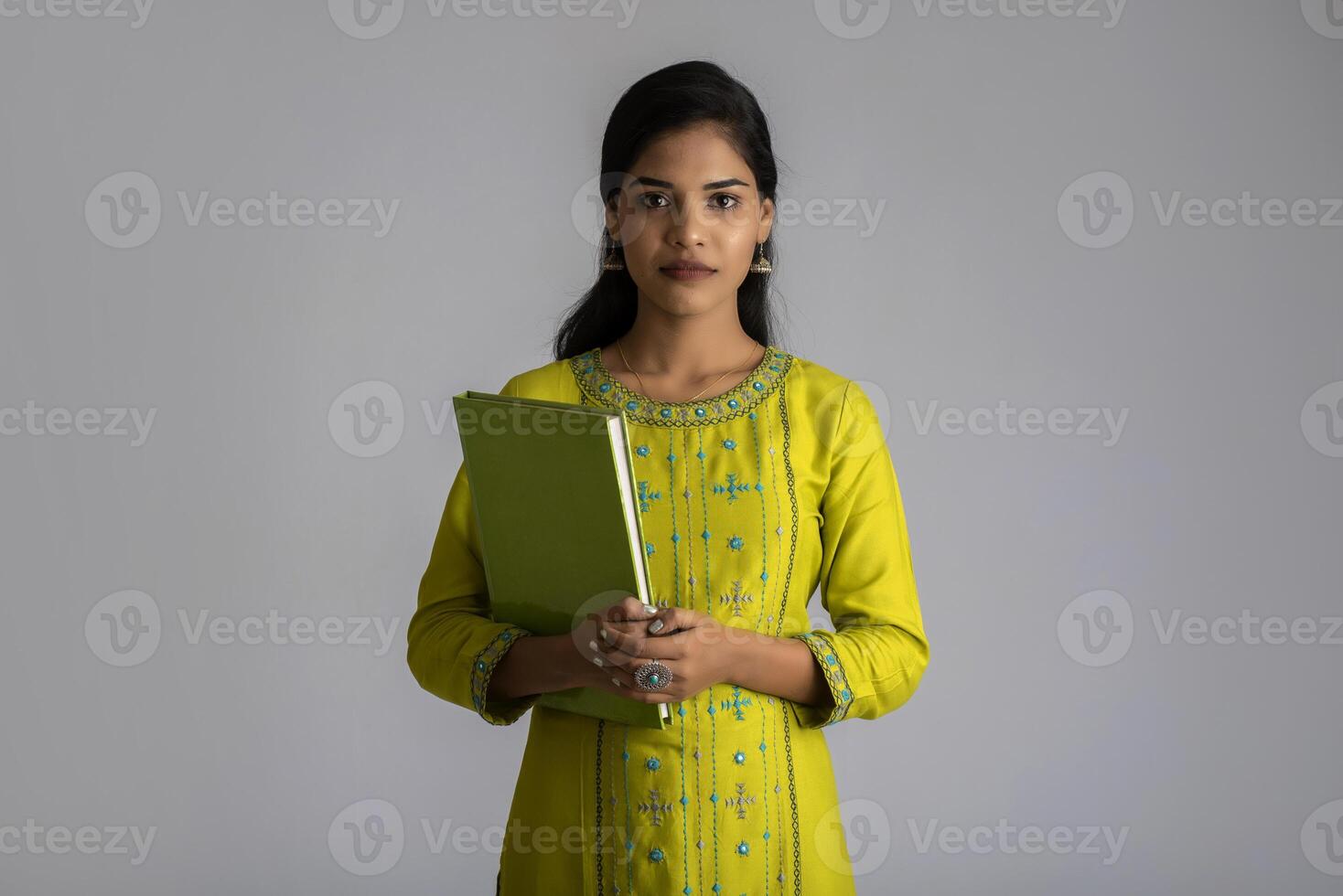 Pretty young girl posing with the book on grey background photo