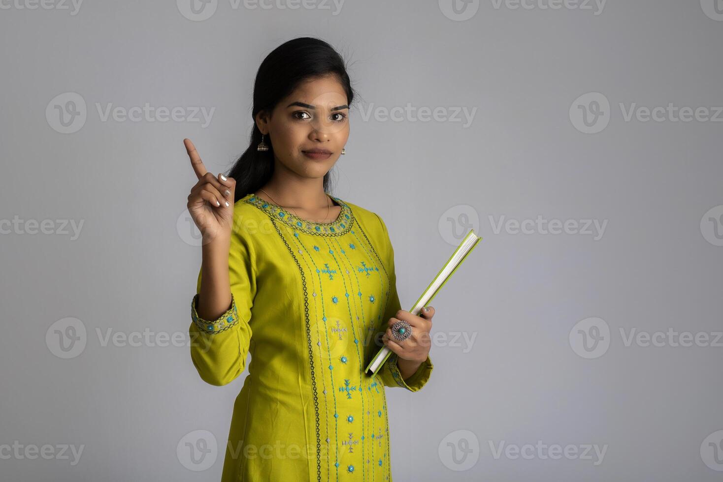 Pretty young girl posing with the book on grey background photo
