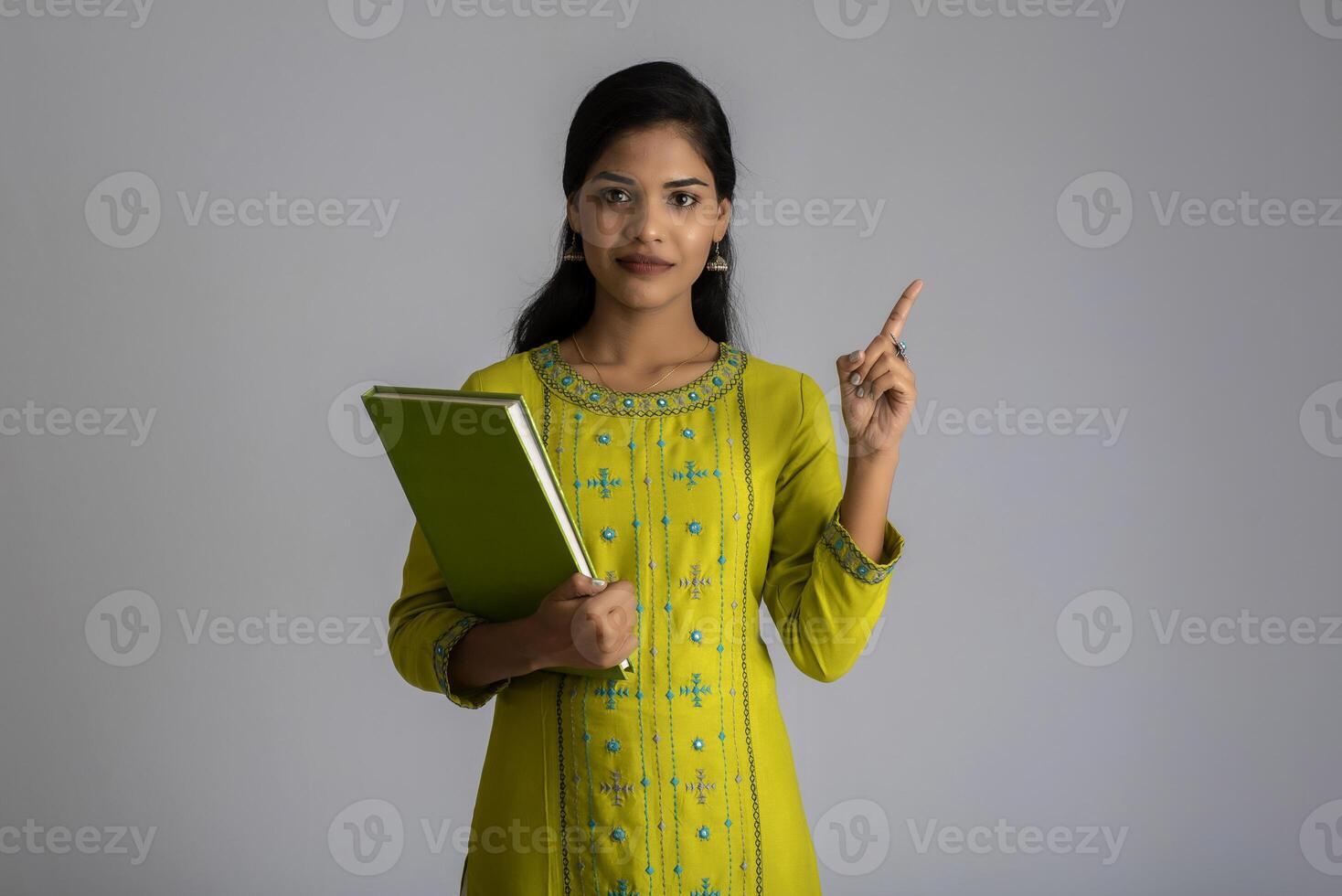 Pretty young girl posing with the book on grey background photo