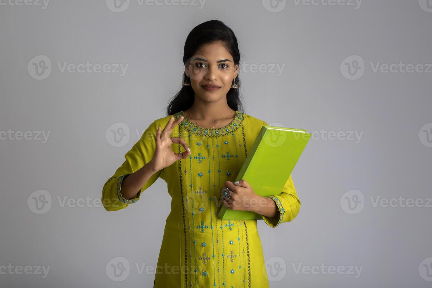 Pretty young girl posing with the book on grey background photo