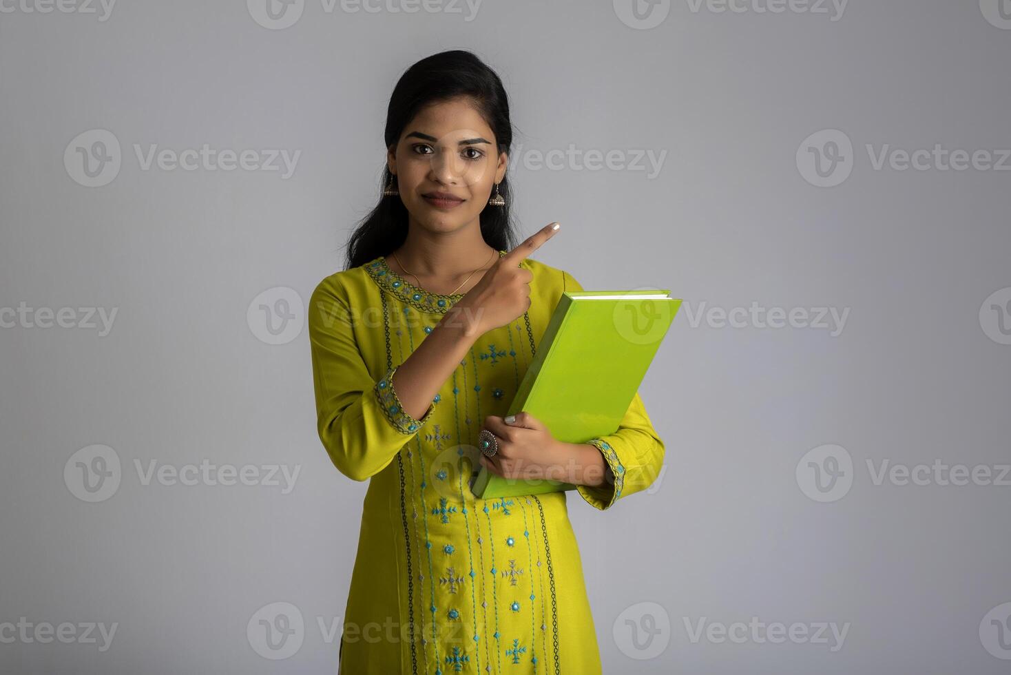 Pretty young girl posing with the book on grey background photo