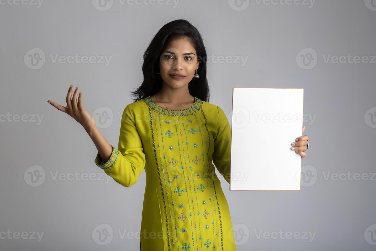 A young girl or businesswoman holding a signboard in her hands on a gray background. photo