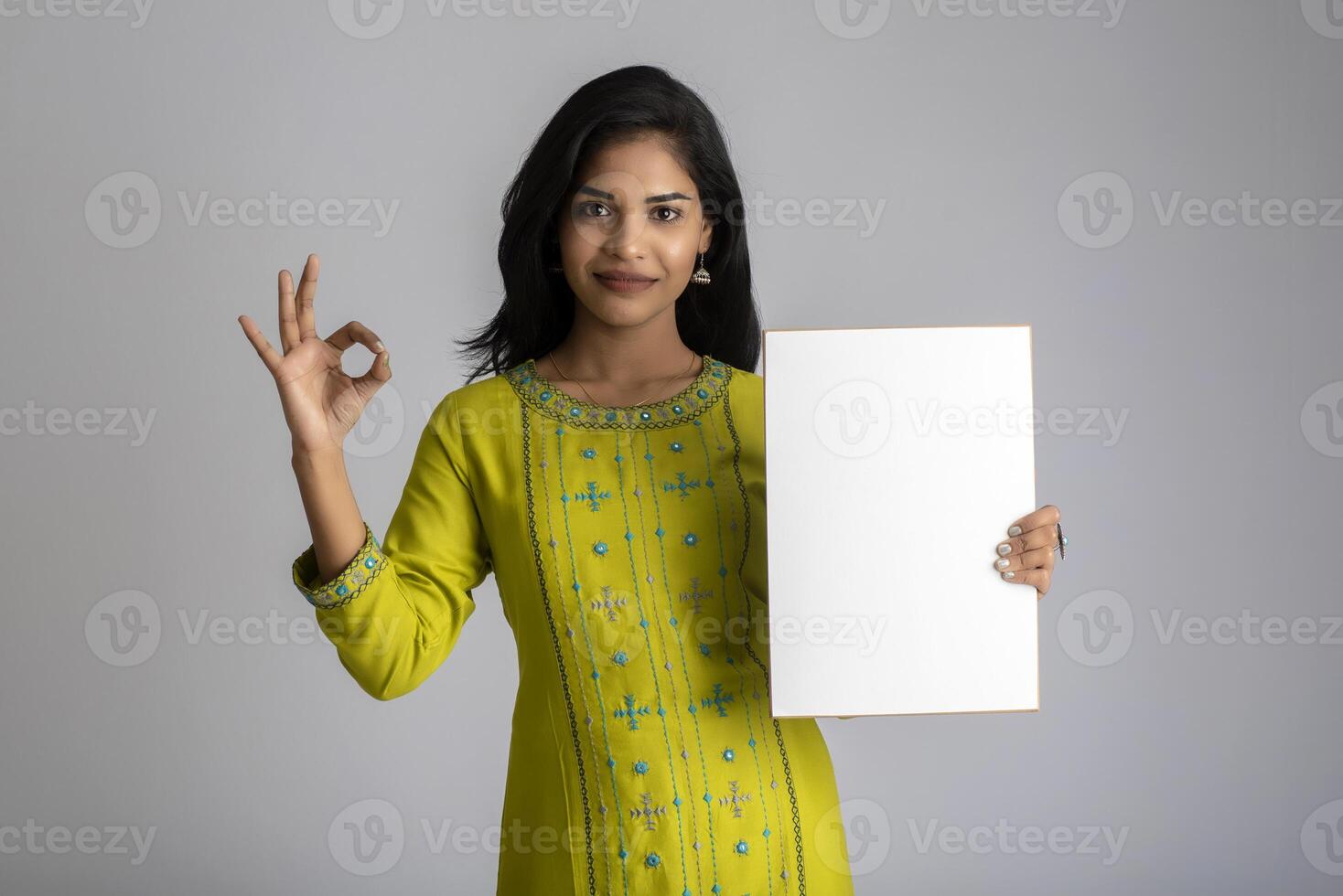 A young girl or businesswoman holding a signboard in her hands on a gray background. photo