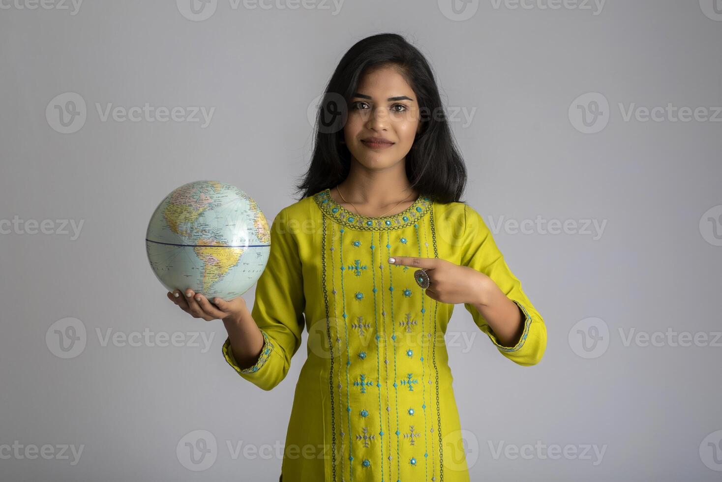 young girl holding the world globe and posing on a grey background. photo