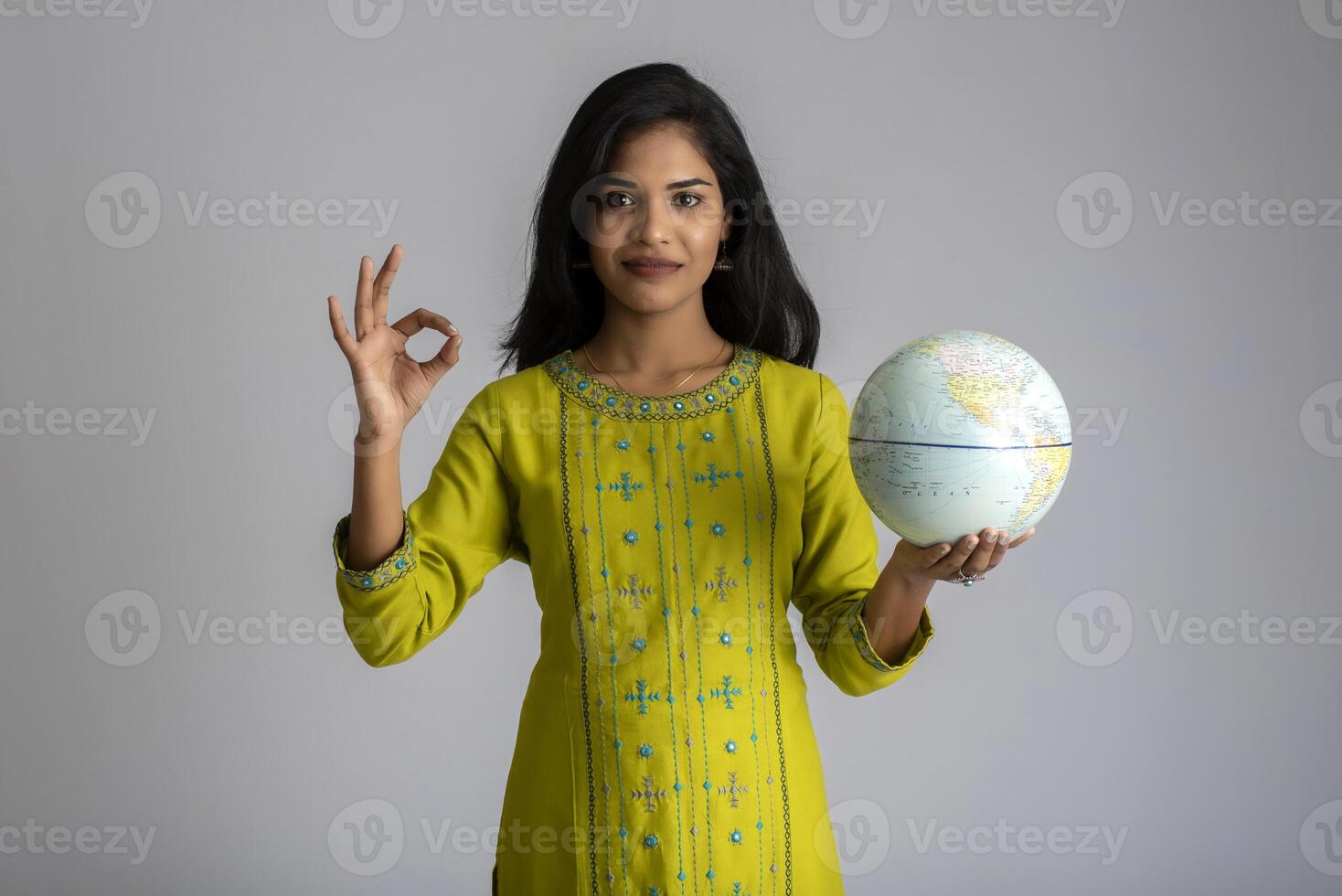 young girl holding the world globe and posing on a grey background. photo
