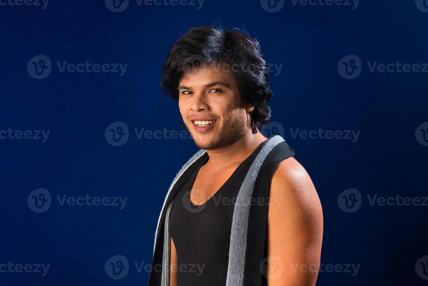 Portrait of a young man posing and showing his muscular body. The concept of a healthy lifestyle on blue background. photo