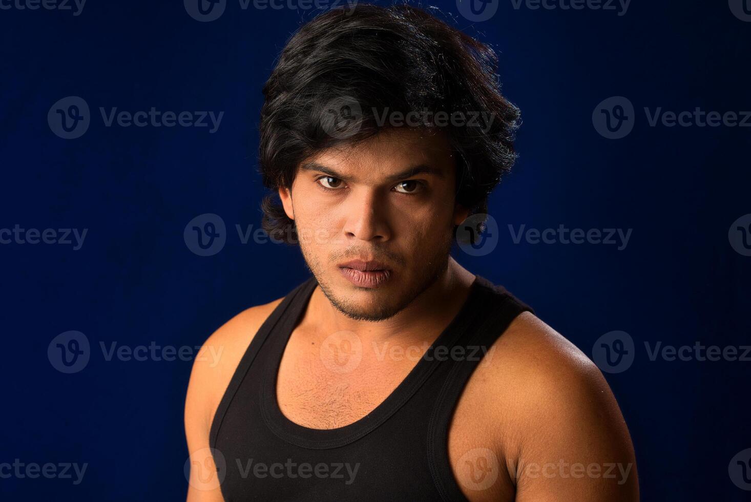 Portrait of a young man posing and showing his muscular body. The concept of a healthy lifestyle on blue background. photo