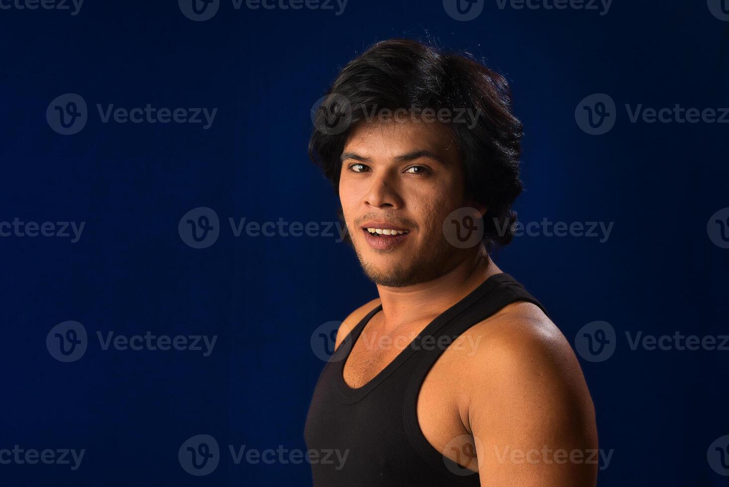 Portrait of a young man posing and showing his muscular body. The concept of a healthy lifestyle on blue background. photo