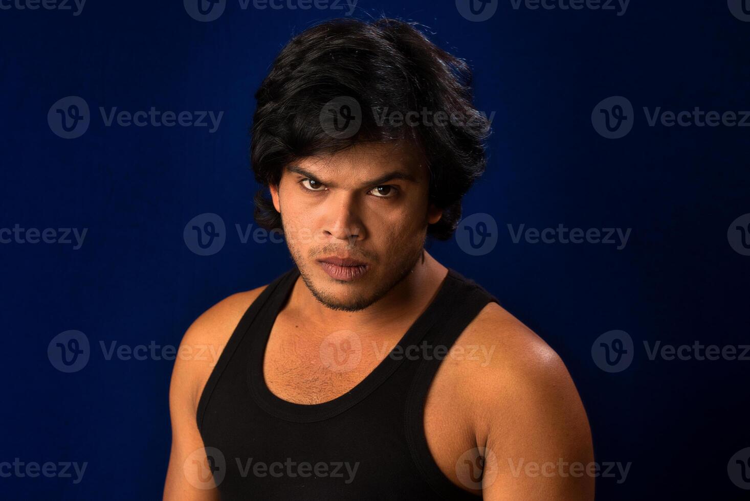Portrait of a young man posing and showing his muscular body. The concept of a healthy lifestyle on blue background. photo