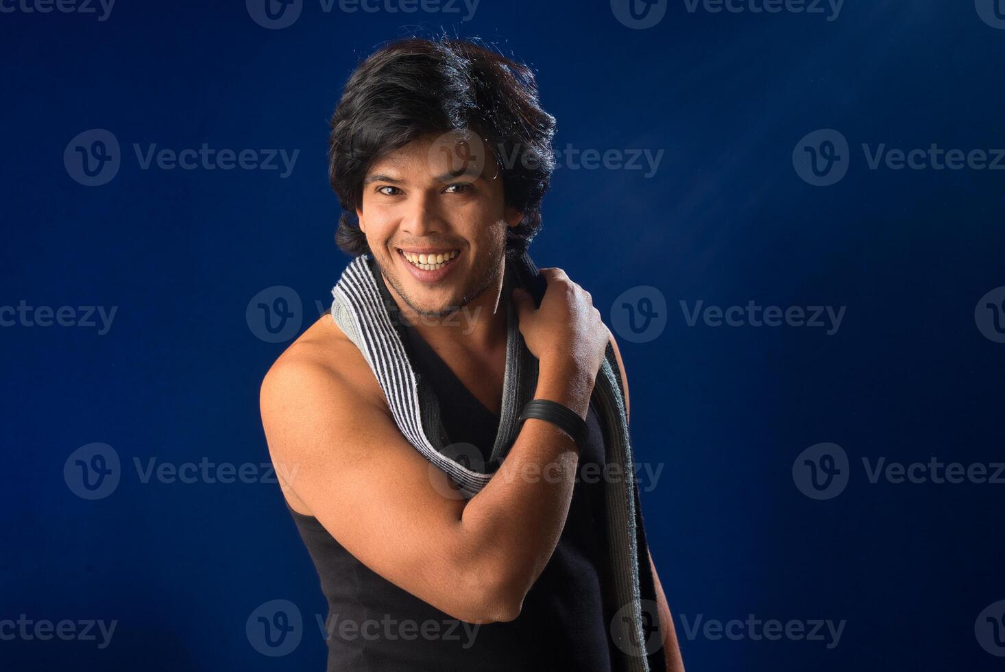 Portrait of a young man posing and showing his muscular body. The concept of a healthy lifestyle on blue background. photo