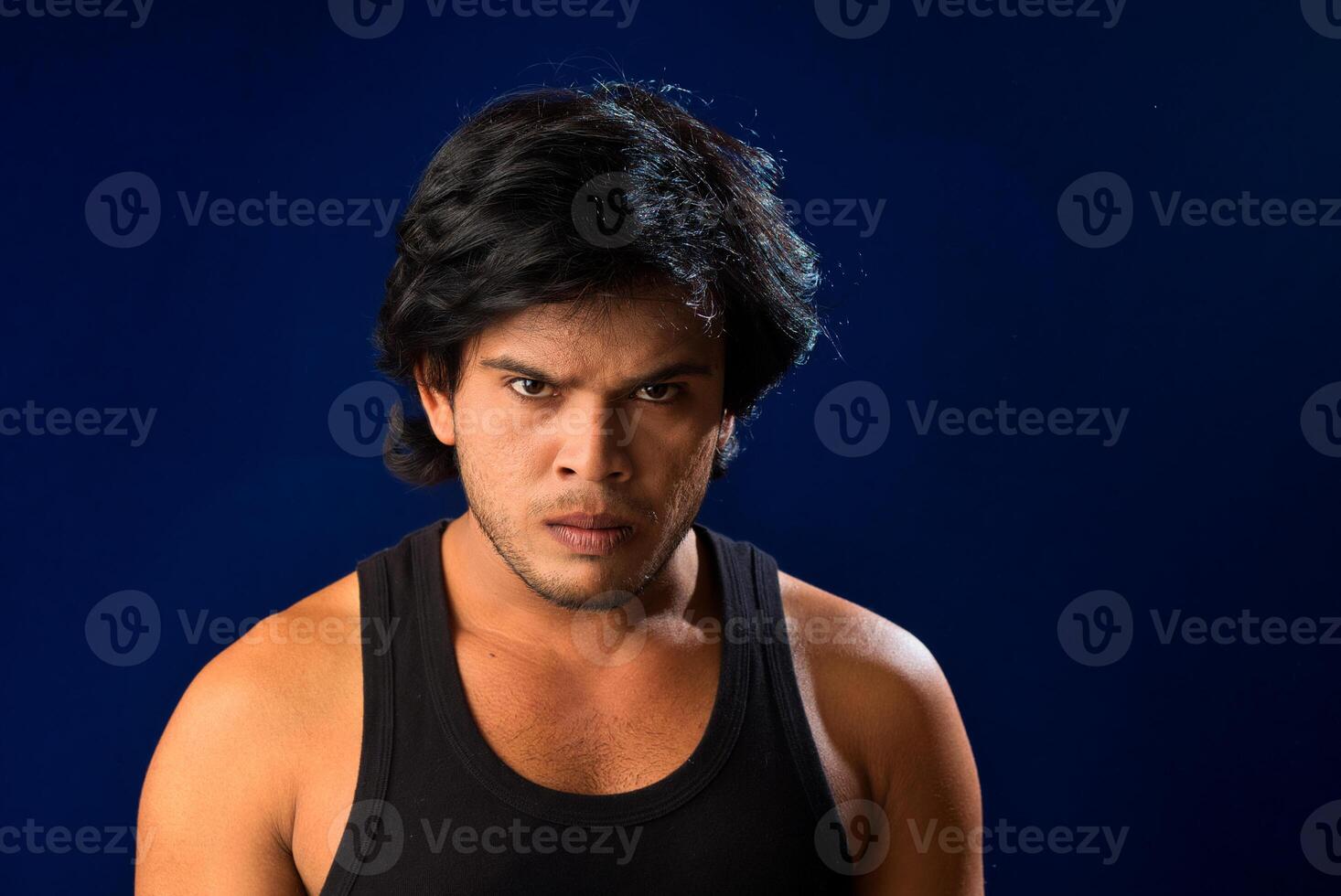 Portrait of a young man posing and showing his muscular body. The concept of a healthy lifestyle on blue background. photo