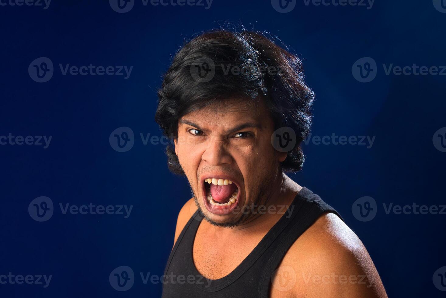 Portrait of a young man posing and showing his muscular body. The concept of a healthy lifestyle on blue background. photo