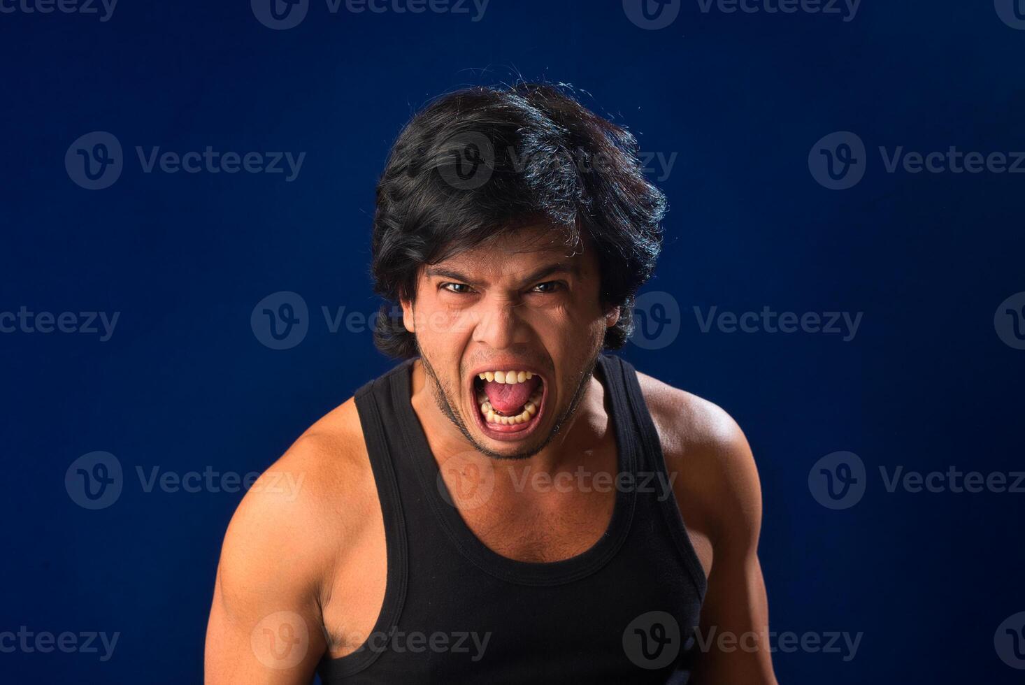 Portrait of a young man posing and showing his muscular body. The concept of a healthy lifestyle on blue background. photo