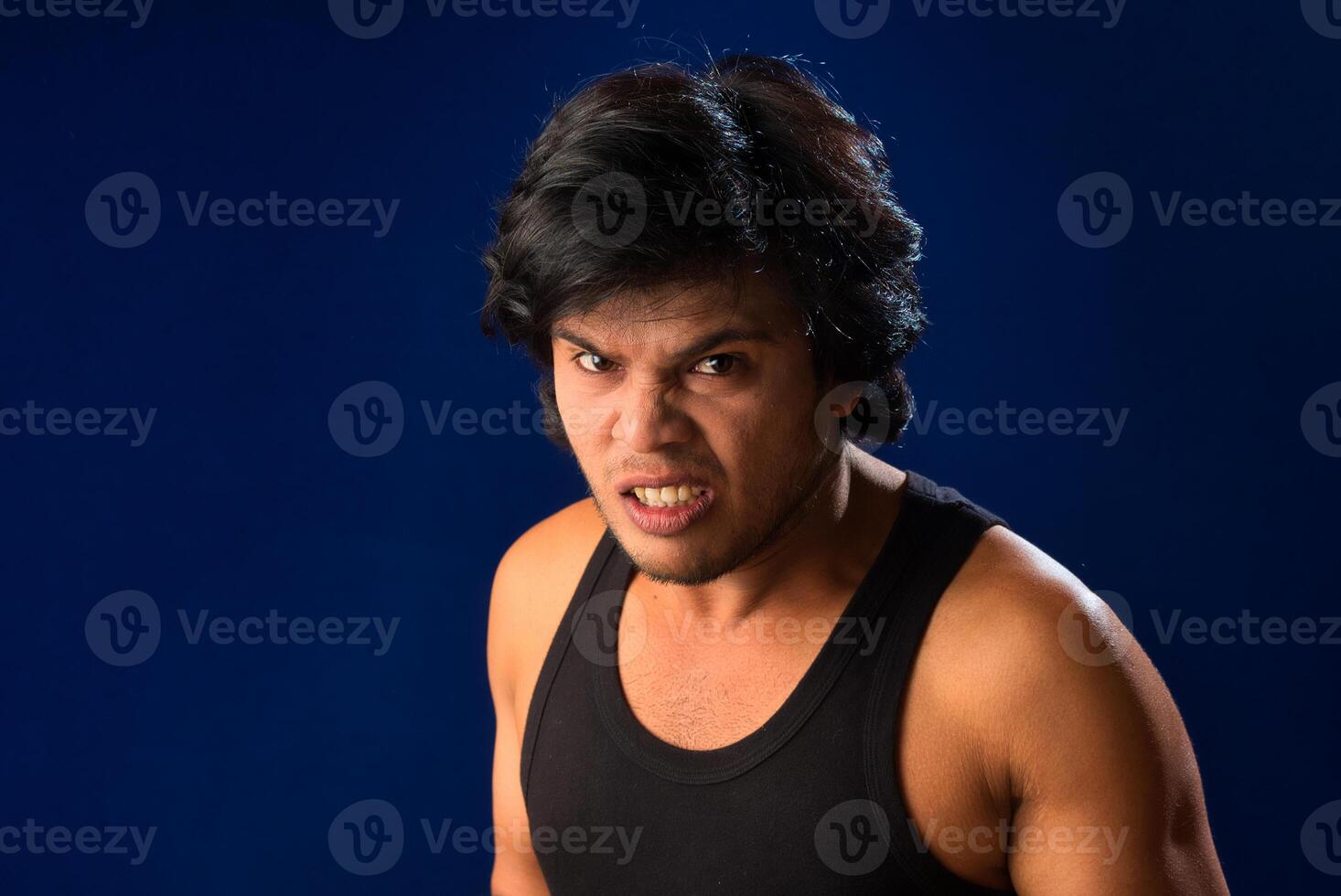 Portrait of a young man posing and showing his muscular body. The concept of a healthy lifestyle on blue background. photo