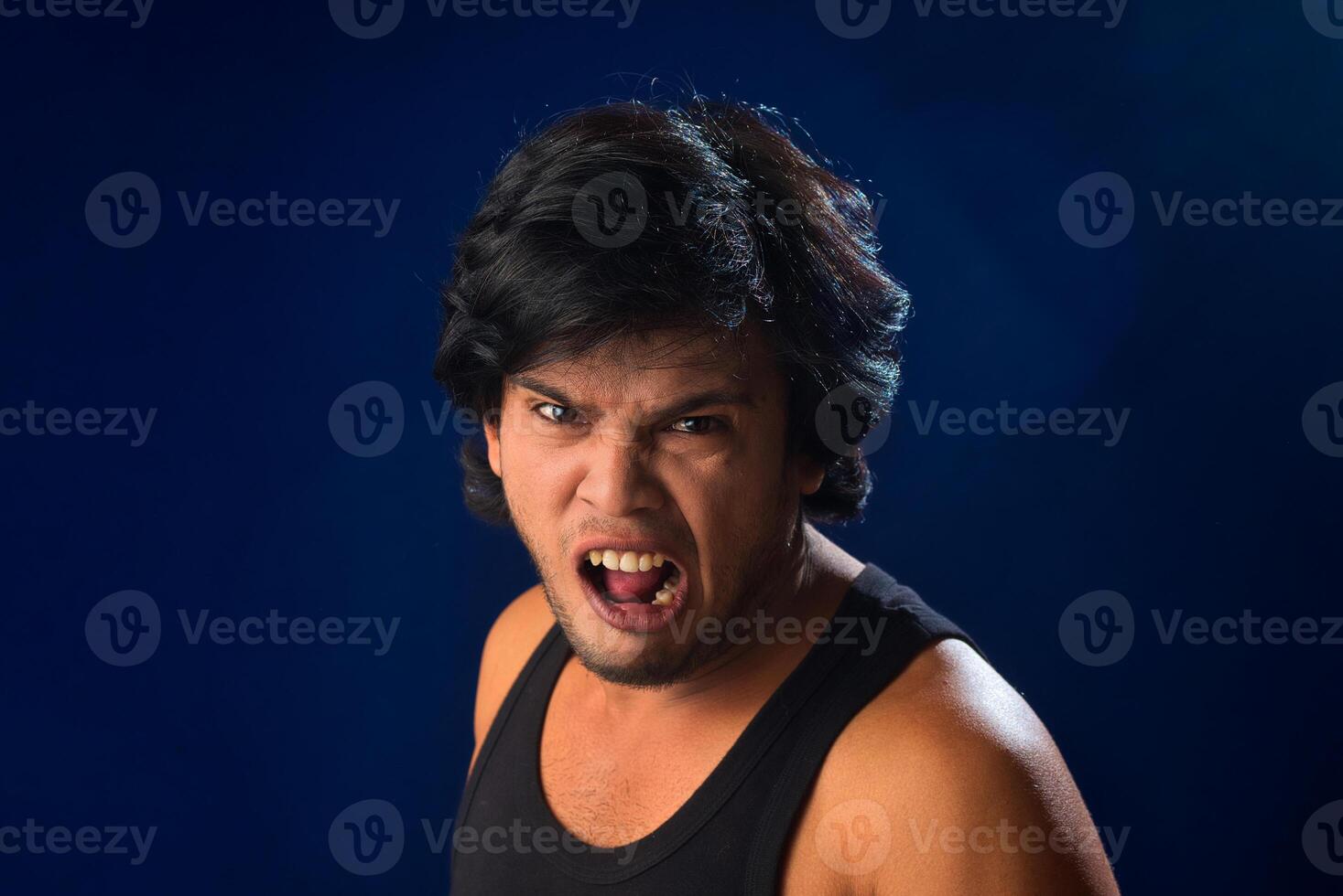 Portrait of a young man posing and showing his muscular body. The concept of a healthy lifestyle on blue background. photo