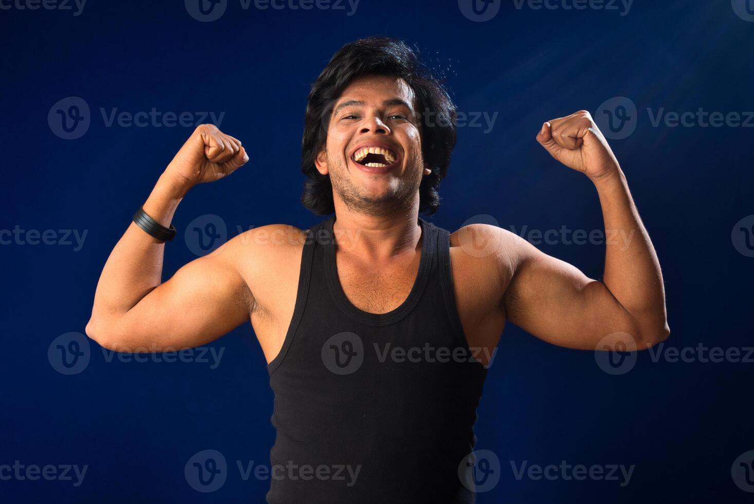 Portrait of a young man posing and showing his muscular body. The concept of a healthy lifestyle on blue background. photo