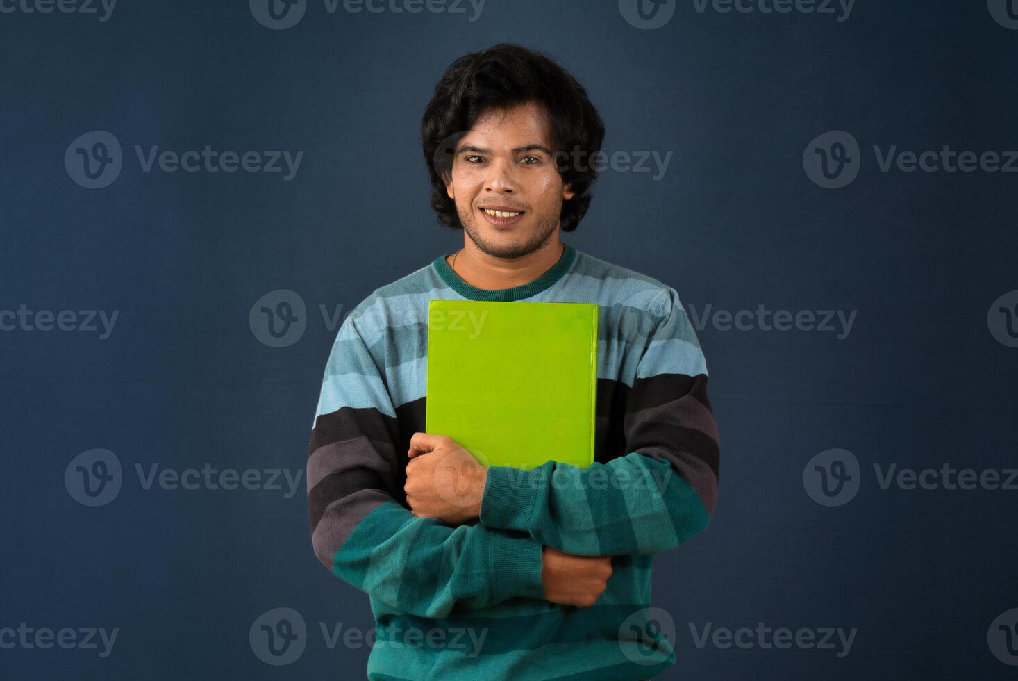 Young happy man holding and posing with the book on background. photo